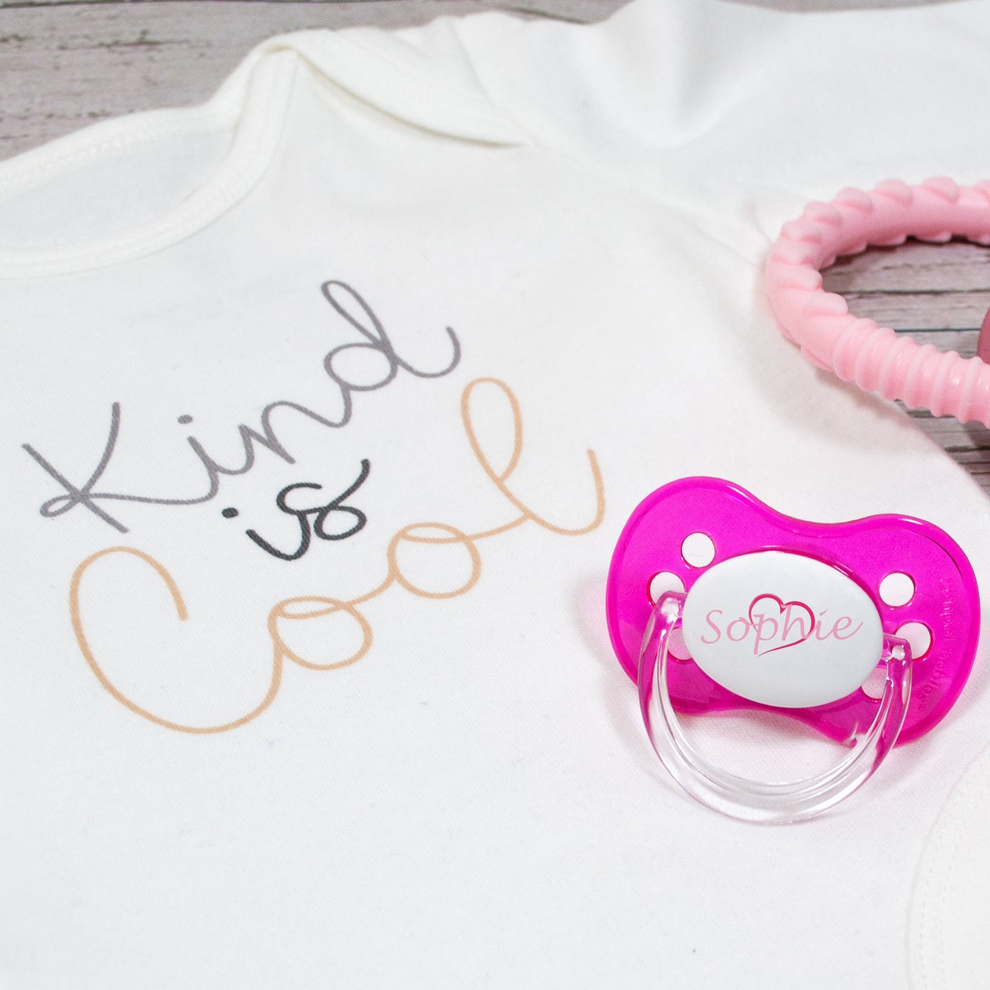 Personalised baby dummy with pink heart and pink name.