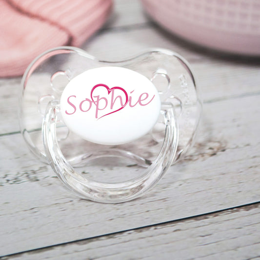 Personalised baby dummy with pink heart and pink name.